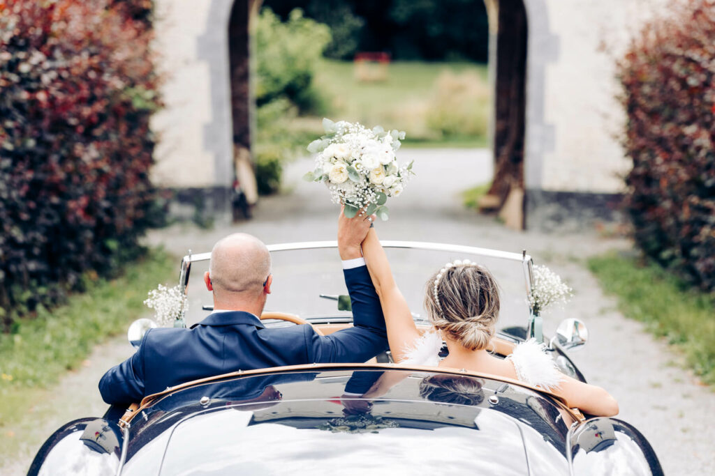 Les mariés de dos dans leur voiture au Domaine Al Poudre